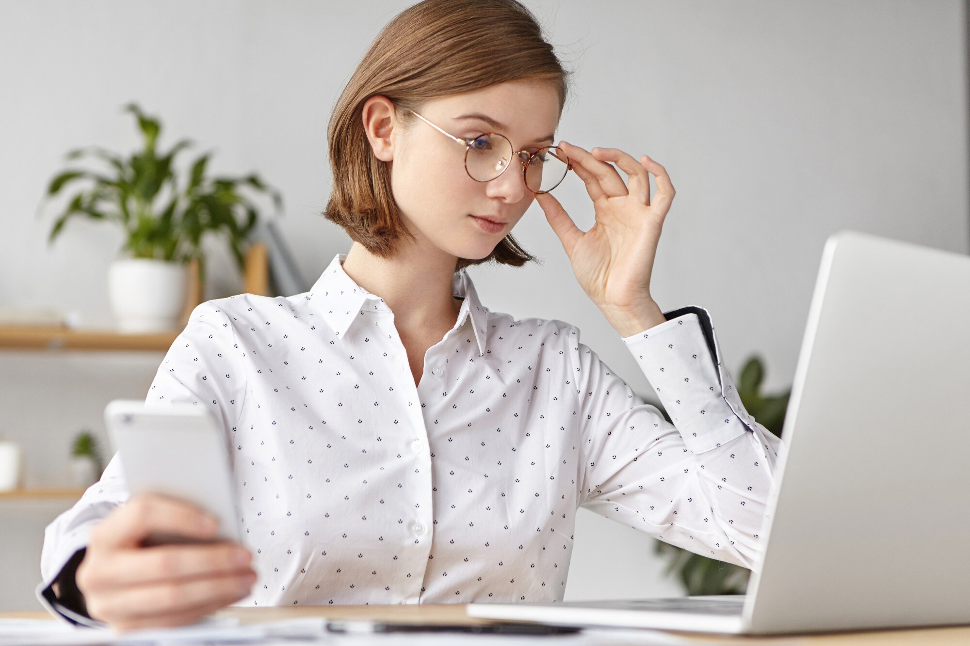 Laptop terbuka di atas meja dengan cahaya alami masuk dari jendela